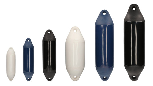 Sechs unterschiedlich große Bootsfender der Marke Plastimo stehen nebeneinander vor weißem Hintergrund. Die Fender sind in verschiedenen Farben (weiß, blau, schwarz) gehalten und haben eine zylindrische Form mit Befestigungsösen an beiden Enden. Sie dienen dem Schutz von Booten beim Anlegen.